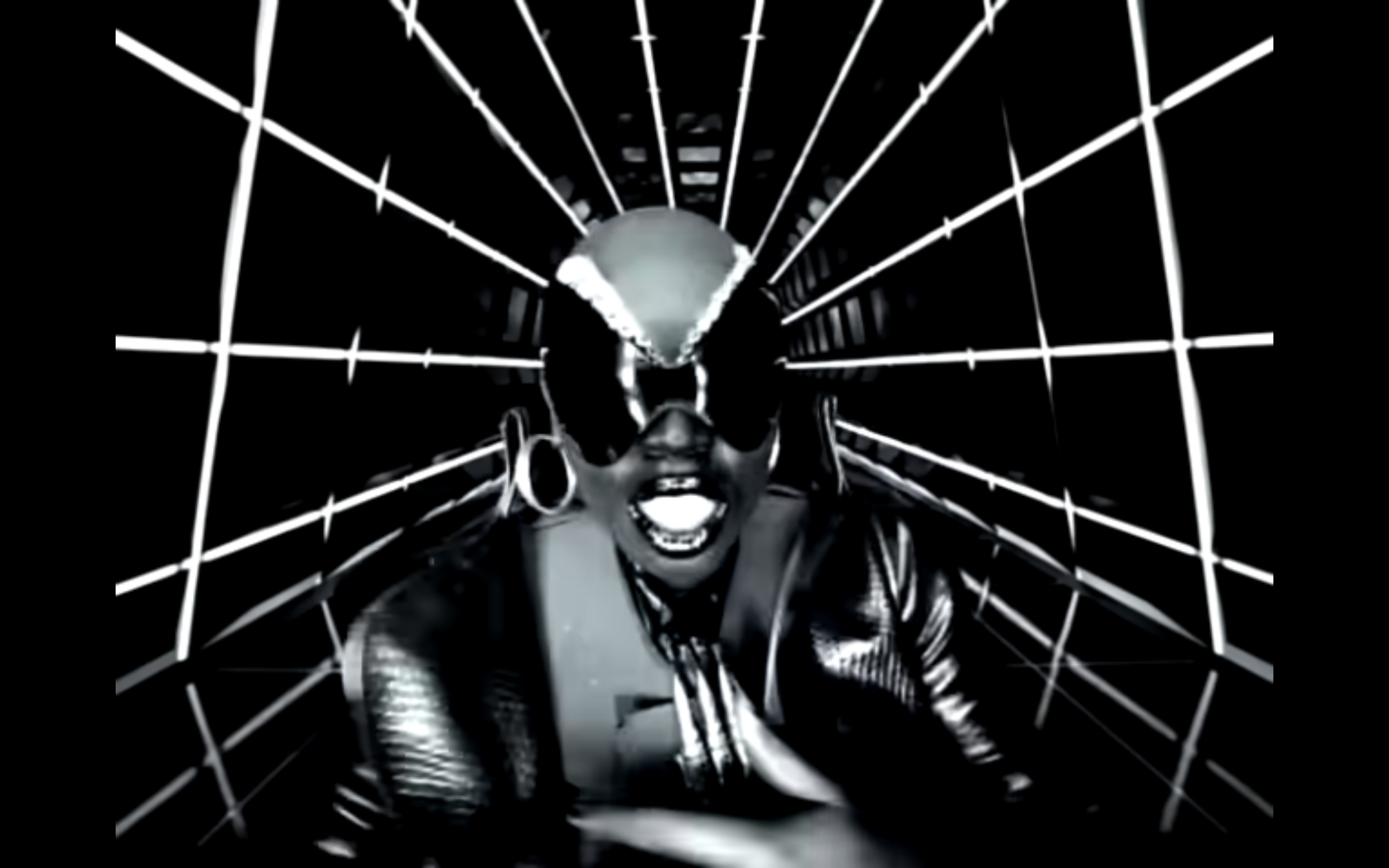 Still from artist Missy Elliott's She's a bxxxx music video. She is dressed in all black, futuristic gear